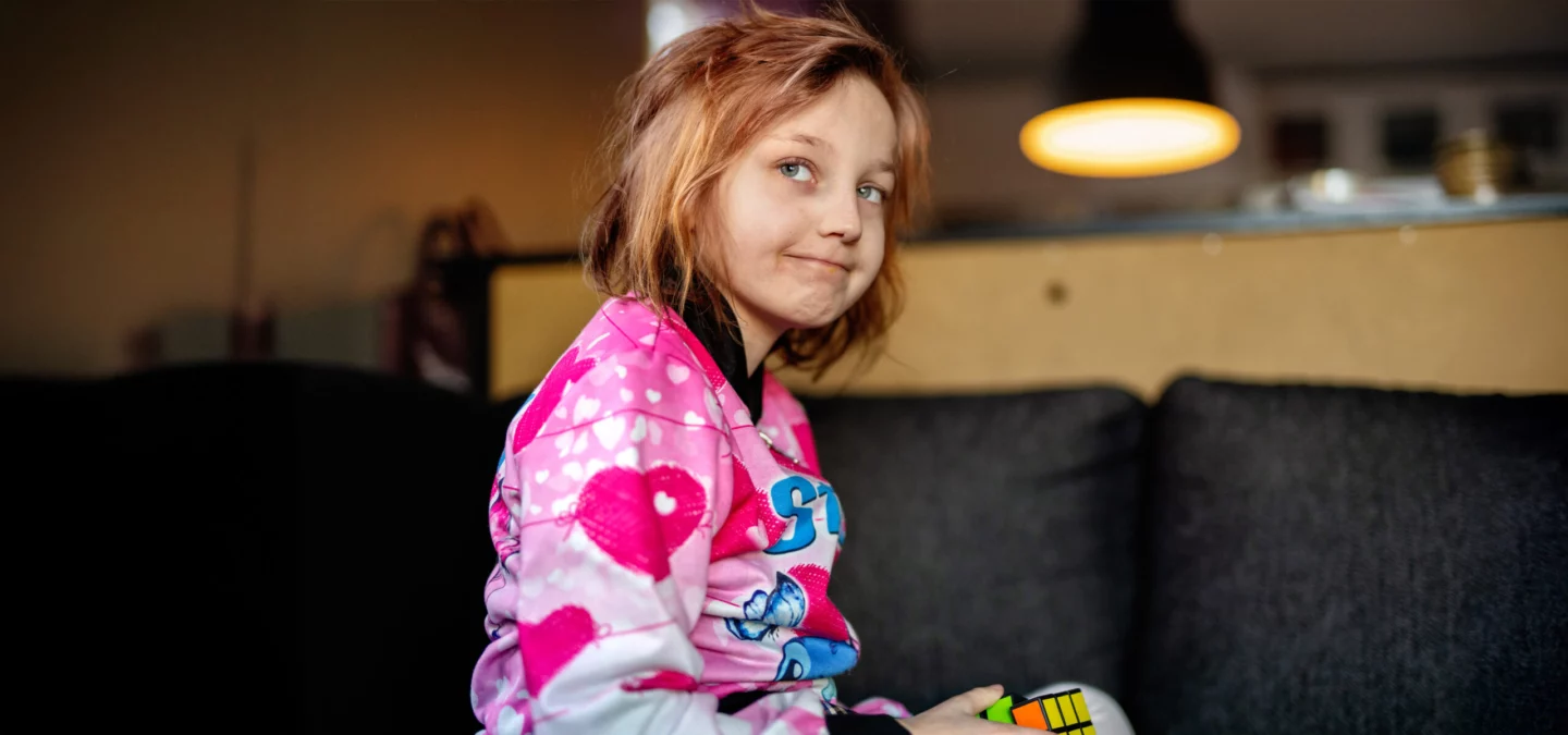 Flicka med rosa tröja sitter i en soffa